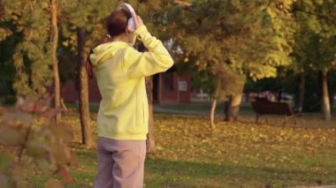 Genç bir kadın, aktif bir atlet kulaklık takıyor, müzik dinliyor, koşuyor, antrenman yapıyor. Koşan sporcu kız, şehir caddesinde koşan. Kadın parkta koşuyor, spor yapıyor, kardinallik yapıyor. Koş ve kilo ver.