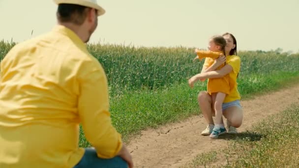 Figlia, la ragazza corre da papà a mamma al sole. Famiglia felice gioca nel campo di grano in estate. Padre bambino madre ricreazione all'aperto, infanzia in famiglia. Weekend con la famiglia, giochi per bambini con i genitori — Video Stock