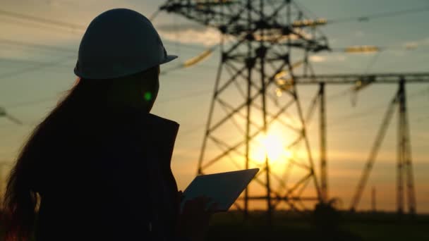 Ingeniera civil, mujer especializada en trabajos de suministro de electricidad al aire libre. Electricidad respetuosa con el medio ambiente. Tecnologías modernas. Ingeniero de potencia en comprobaciones de casco de seguridad línea de alimentación, tableta digital — Vídeos de Stock