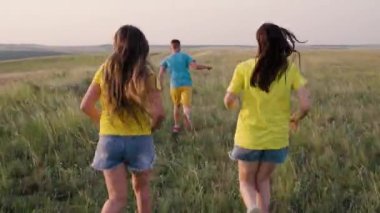 Yazın, mutlu çocuklar koşup sahada oynarlar. Bir grup genç, parkta güneşlenip neşe dolu mutluluğu kutluyorlar. Mutlu aile, çocuklar, birlikte koşmak. Çocuklar koşuyor.