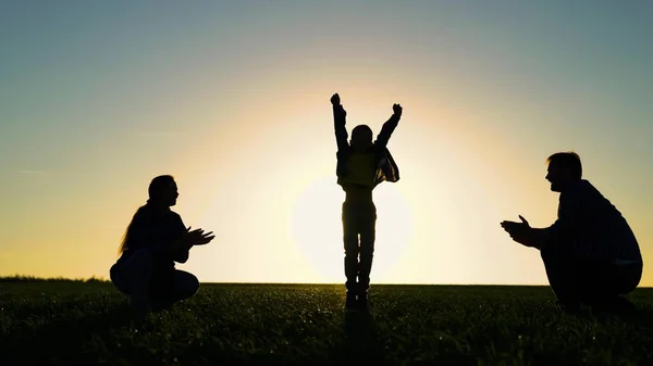 Figliolo, il ragazzo salta rallegrandosi cammina con mamma papà al parco al sole. Emozioni gioiose di figlio bambino, famiglia felice che gioca sul campo al tramonto. Padre, bambino madre natura vacanza, infanzia in famiglia. Weekend in famiglia — Foto Stock