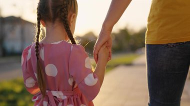 Anne, çocuk ve kız el ele tutuşarak şehir caddesinde yürüyorlar. Mutlu aile kaldırım boyunca yürür, çocuk, kız, anne dışarıda. Hayaller, mutlu aile, çocukluk. Mutlu aile, aile değerleri