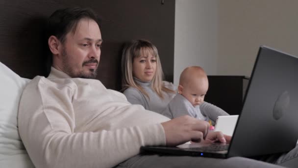 Dad is freelancer working at home at computer, Mom is playing with child. Family with child working at home on computer child with digital tablet. Home office, modern education for children — Stock Video