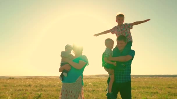 Grote gelukkige familie speelt in het park in de zon. Gelukkig familie team loopt samen hand in hand buiten. Kinderen, zonen, hou mama vader met de hand vast, Teamwork. Groep mensen van verschillende leeftijden bij zonsondergang — Stockvideo