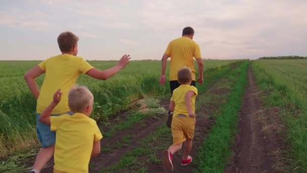 Šťastný rodinný tým, který běží společně v terénu a radostně mává rukama. Synové, děti, máma, táta utíkají, hrají si, radují se, užívají si v létě přírodu. Rodinná týmová práce. Skupina lidí různého věku — Stock video