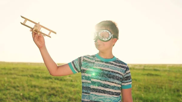 Мальчик в очках играет самолет на закате, счастливая семья, ребенок мечтает летать на солнце, ребенок стремится фантазировать в творческой игре на открытом воздухе природы, веселый сын игрушки, праздник воображения — стоковое фото