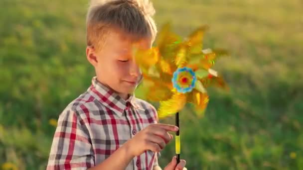 Pequena criança brinca com arco-íris plataforma giratória, família feliz, alegre criança fantasia com brinquedo colorido, pegando direção do vento, menino filho segura em sua mão brilhante círculo multicolorido cintilante no sol — Vídeo de Stock