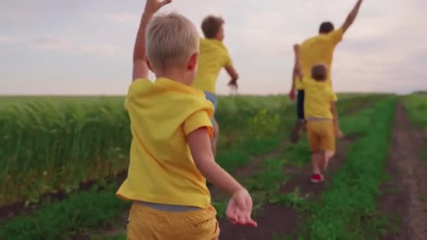 Glückliche Jungen rennen über die Straße, holen ihren Vater ein, spielen mit der ganzen Familie zusammen, haben Spaß an der Natur, fantasieren mit ihren Söhnen und heben die Hände — Stockvideo