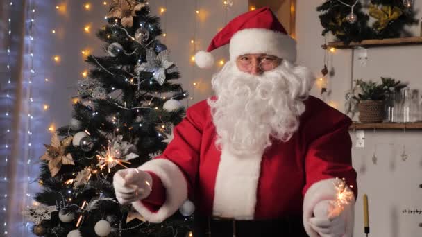 Feliz Santa Claus está bailando con bengalas, disfrutando de la música. Satna Claus se está divirtiendo en la habitación con el árbol de Navidad. Feliz, mágico, niños, vacaciones en familia, Navidad. Año Nuevo, Navidad — Vídeos de Stock