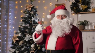 Noel Baba elinde bir bardak köpüklü şarap tutarak mutlu Noeller diliyor. Aile Noel tatili. Noel Baba ve Noel gecesi. Noel Baba 'nın evinde Noel ağacı. Yeni yıl tatili, eğlenceli parti.