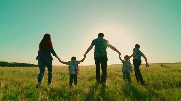 Une famille heureuse court dans le parc en se tenant la main. Bonne silhouette familiale de promenade des parents et des enfants au coucher du soleil. Maman, papa fils marchent ensemble à l'extérieur. Vacances en famille dans la nature, rêves et fantasmes d'enfants Photos De Stock Libres De Droits