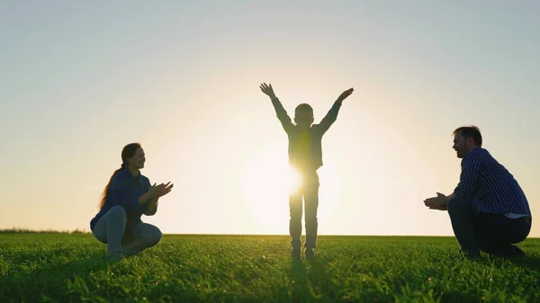 Figlio, ragazzo che salta, si diverte a passeggiare con mamma papa 'al parco al sole. Emozioni gioiose del piccolo figlio, famiglia felice che gioca sul campo al tramonto. Padre, figlio, madre, natura, infanzia in famiglia. Weekend in famiglia — Foto Stock