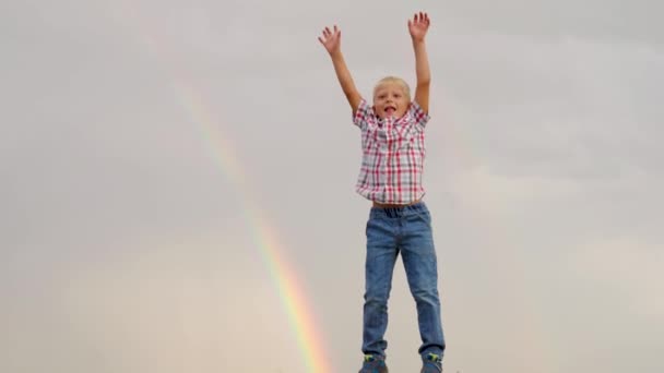 Kind, jongen, speelt, heeft plezier buiten. Gelukkig kind stak zijn handen op naar de hemel, springt vrolijk in het zomerpark voor de regenboog. Gelukkige kindermomenten, spelen in de natuur. Gelukkige kindertijd, opgroeiende kinderen — Stockvideo