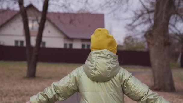 かわいい女の子の子供は、美しい秋の通りの家に沿って実行されます。子供は秋に公園で遊ぶ。幸せな子供の休日。幸せな家族は公園を歩く。子供が走り回る子供の剣 — ストック動画