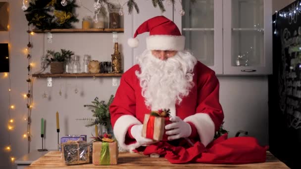 Счастливый Санта Клаус ловит коробку с подарком и вручает ее публике. Санта Клаус веселится в комнате, на рождественских каникулах. Счастливого, волшебного, детского семейного праздника Рождества Христова. Новый год — стоковое видео