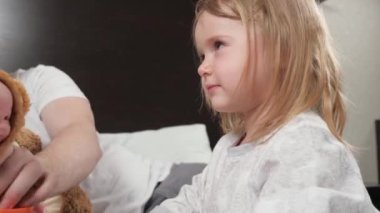 Baba, çocuk, kız ve çocukların en sevdiği oyuncakla oynar, birlikte güler ve eğlenir. Evde mutlu bir aile. Bebek evde babasıyla kanepede gülüp oynuyor. Evde eğitim