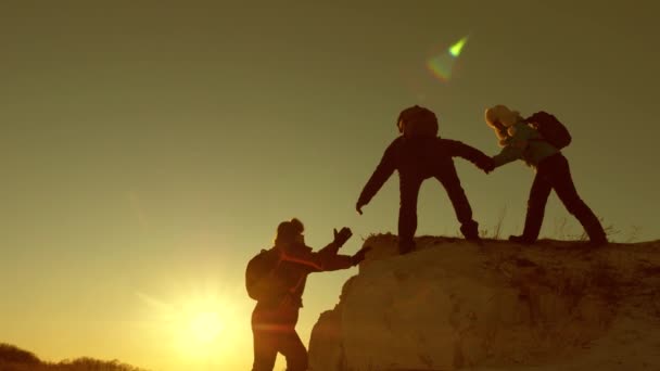 Reizigers beklimmen elkaar op de rots. Teamwork van zakenmensen. Klim silhouetten strekken hun handen naar elkaar, klimmen naar de top van de heuvel. Een team van zakenmensen gaat winnen.. — Stockvideo