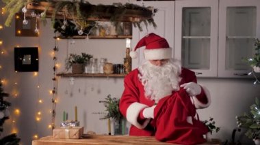 Yaşlı komik Noel Baba, hediye kutularını bir çantaya koyar. Ailenin en sevdiği kış tatili. Noel Baba 'dan Noel hediyeleri. Mutlu noeller. Santaclaus hediye teslimatı. Şenlikli yeni yıl havası. Noel Baba hediye getirir.