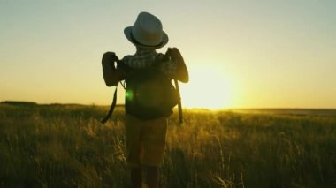 Gezgin olmayı hayal eden bir çocuğun silueti, gün batımında bir tarlada oynayan bir çocuk. Küçük çocuk yaz parkında sırt çantasıyla seyahat ediyor. Çocuk dışarıda yürüyor. Çocukluk, rüyalar keşifler