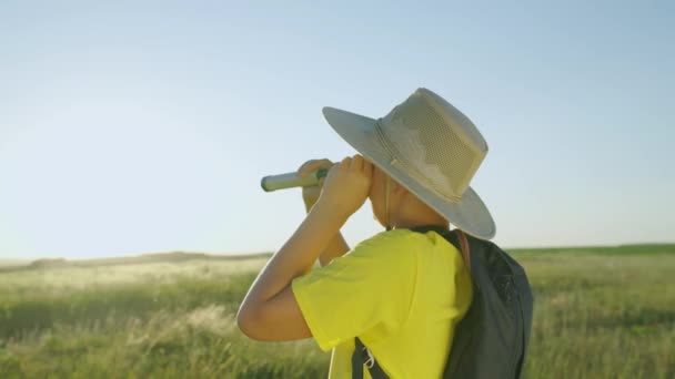 Enfant, fils, rêves de voyageur, fantasmes de terrain de jeu. L'enfant joue dans la nature comme découvreur. Joyeux petit garçon jouant dans le parc dans un chapeau regarde à travers un verre d'espion en plein air d'été.. — Video