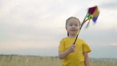 Dışarıda eğlenceli yel değirmeni pikabı oynayan mutlu çocuk. Aile tatili. Küçük kız, sonbaharda parkta elinde çok renkli bir pikap ile oynuyor. Mutlu aile hafta sonu doğada dinleniyor.