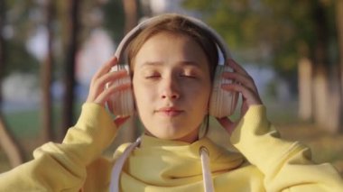 Dışarıda sonbaharda kulaklıkla müzik dinleyen çekici genç bir kadın. Parkta müzik dinleyen güzel bir kız. Genç kız müzik müziğinin tadını çıkarıyor, kız dans ediyor. Mutlu yetişkin kız..