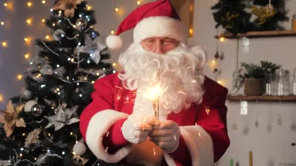 Ο Άγιος Βασίλης χορεύει με βεγγαλικά για να γιορτάσει τα Χριστούγεννα. Καλά, μαγικά, παιδικά, οικογενειακές διακοπές, Χριστούγεννα. Ο Άγιος Βασίλης διασκεδάζει σε ένα δωμάτιο με ένα χριστουγεννιάτικο δέντρο. Πρωτοχρονιά Χριστούγεννα — Αρχείο Βίντεο