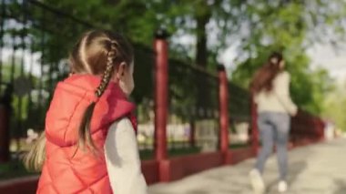 Mutlu bir aile kızı, gün batımında parkta koşan bir çocuk. Anne ve çocuk parkta oynuyorlar. Anne sokakta birlikte koşmak için kızıyla oynuyor. Aile açık hava koşusu.