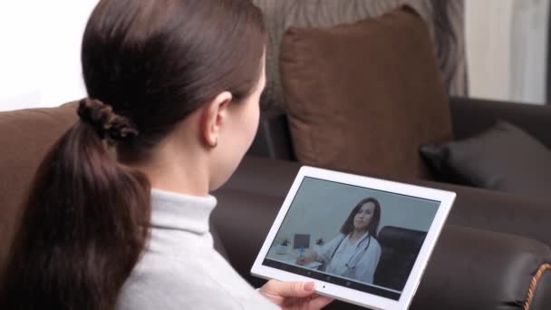 Профессиональный врач лечит пациента в онлайн видео чате. Молодая женщина заболела дома, используя цифровой планшет, чтобы поговорить со своим врачом. Приложение для видеоконференций. Семейный врач — стоковое видео