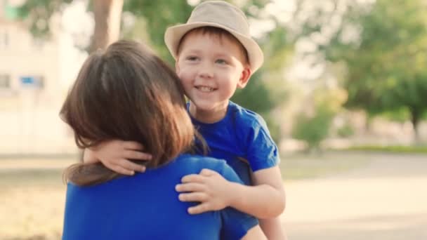 Child, son runs to mom and hugs her in the park on the street in summer. A happy family. Carefree childhood, joyful running of the baby to his mother. Kid playfully plays in the spring on the street — Stock Video