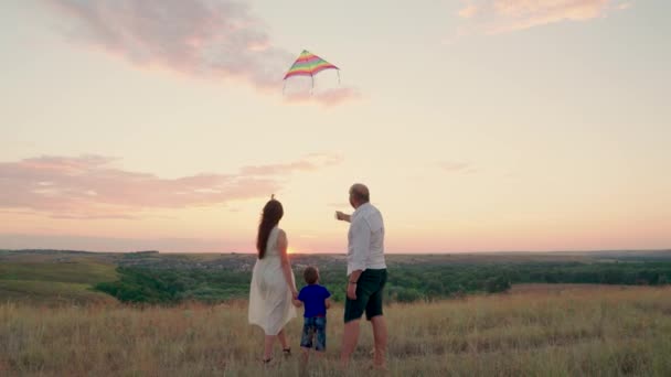 Een gezin met een kind speelt in het voorjaar samen in het park en vliegt met een vlieger de lucht in. Familie geluksconcept. Mam, kind, zoon, vader reist. Kind speelt met ouders, kinderdromen — Stockvideo