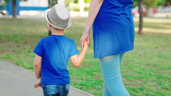 Mom, child, son walk along the path together, holding hands in the park. Family walk, baby, boy, mother, spring outdoors. Dreams, happy family, childhood. The concept of a happy family, family values — Stock Photo, Image