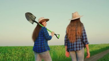 Ellerinde kürekle çiftçi kadınlar tarlada çalışıyor, konuşuyor ve hasadı kontrol ediyorlar. Günbatımında kadın çiftçi, tarım uzmanı olarak çalışıyor. Tarım sektörü konsepti. Kadın işadamı