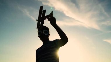 Siluet, pilot gözlüklü bir çocuk oyuncak bir uçakla oynuyor, gökyüzünün karşısında. Bir çocuk uçak uçurmayı hayal eder. Çocukların fantezi seyahatlerinin konsept ailesi. Oğlum pilot olmayı hayal ediyor.