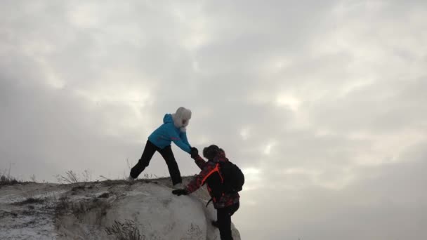 Poutníci lezou na skálu společně. Týmová práce obchodníků. Obchodní tým vyhrává. Turističtí horolezci muž a žena natahují ruce k sobě, pomáhají vylézt na vrchol kopce. — Stock video