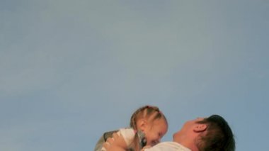 Babam mutlu kızını mavi gökyüzüne fırlattı. Baba ve çocuk yaz parkında birlikte oynuyorlar, gülüyorlar ve sarılıyorlar. Kaygısız çocuk gökyüzüne uçuyor. Babamın izin günü. Mutlu aile kavramı