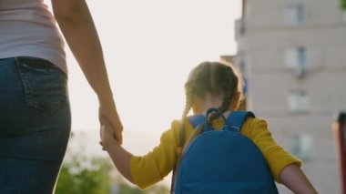 Bir kız, liseli bir kız, sırt çantasıyla sokakta yürüyor, annesini elinden tutuyor. Mutlu aile, anne ve çocuk el ele tutuşarak okula gider. Çocuk öğrenme kavramı