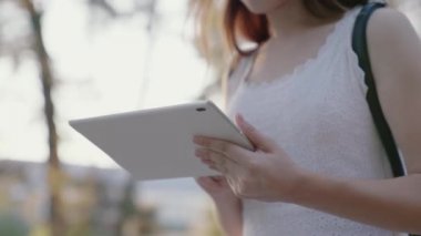 Öğrenci elleriyle tabletin dokunmatik ekranına dokunur. Şehirde tablet bilgisayarla çalışan serbest çalışan bir kadın. Gençlerin modern aletleri kullanma kavramı.