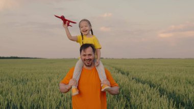 Mutlu aile, kız ve baba buğday tarlasında birlikte oynuyorlar. Çocuk elinde oyuncak bir uçak tutuyor. Çocukluk hayali olan uçma ve pilot olma fikri. Baba ve çocuk.