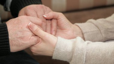 Genç bir kadın yaşlı bir adamın elini tutuyor. Yetişkin bir kadının, kızının, torununun avuç içleri yaşlı bir babanın, büyükbabanın bir erkeğin elini tutuyor. Aşk bakımı, yaşlı ebeveynlere yardım