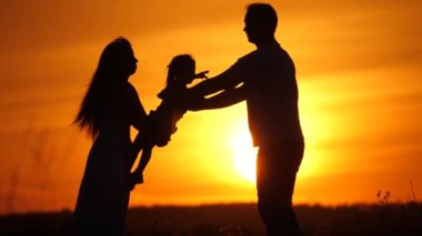 Mutlu bir aile gün batımında parkta bir çocukla oynuyor. Babam sevgili kızının etrafında güneş ışınlarıyla daireler çiziyor. Anne, baba ve bebek yazın tarlada eğleniyor. Ebeveynler, çocuklar.