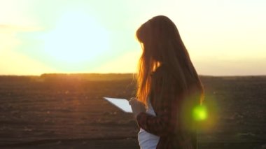 Bilgisayar tabletli çiftçi kadın baharda ekmeden önce tarlayı kontrol ediyor. İş kadını sahada çalışıyor. Bir tarlada çiftçi bir kadın sonbaharda ekilen tahılların kalitesini kontrol eder.