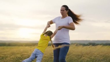 Anne sonbaharda gün batımında mutlu kızıyla parkta oynuyor. Anne, çocuk, döndürün, gülün, sevinin. Mutlu aile gezileri. Ailesinin kollarında bir çocuk. Çocukluk mutluluğu, annelik kavramı.