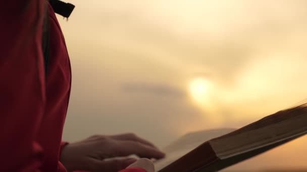 Mladá žena čte knihu v parku na podzim v paprscích západu slunce. Modlitba v přírodě. Student čte učebnici v přírodě na jaře. Muž čte venku knihu. Studium, vzdělávání — Stock video