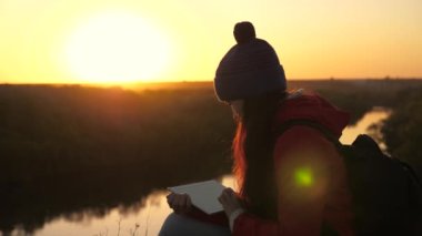 Genç kız öğrenci doğada bir tabletle seyahat ediyor, uzaklardan öğreniyor. Güzel bir turist blogcusu, sonbaharda dijital tablet kullanarak parkta online bir röportaj yazıyor..