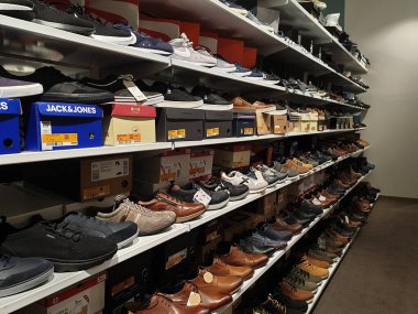 Hoogstraten, Belçika - 2 Ekim 2021: Belçika 'da bir mağazadaki erkekler için ayakkabı dolu bir rafın portresi. Ayakkabı tüm renkler, boyutlar ve markalar için mevcuttur..