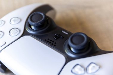 BRECHT, BELGIUM  AUGUST 14 2022 Close up portrait of the sticks of a white basic playstation 5 controller which is charging with the official USB-C cable. The ps5 device is lying on a wooden table.