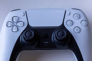 Brecht, Belgium August 12 2022: A portrait of a basic white sony playstation 5 wireless controller lying on a white surface. The ps5 gaming device is charging.