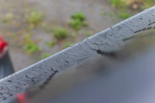 A portrait of a roof gutter overflowing with water during a rainy day. The rain water can not be drained, because the gutter is clogged with branches, leaves and twigs of trees and needs to be cleaned
