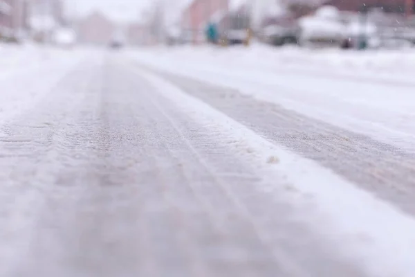 冬の間に雪と氷に覆われたアスファルトの道路や通りの低肖像画 白い表面には凍結したタイヤトラックが見えるので 運転するのは非常に滑りやすく危険です ロイヤリティフリーのストック写真